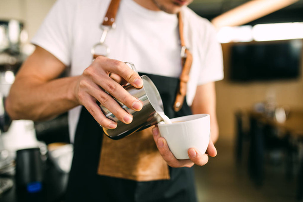 Διαδικασία παρασκευής φρέσκου καφέ. Επαγγελματίας barista ρίχνει γάλα σε φλιτζάνι καφέ espresso. - Φωτογραφία, εικόνα