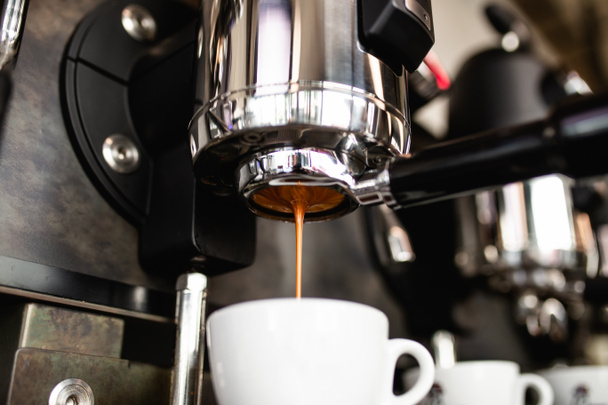 Espresso que vierte de la máquina de café en la taza de café
. - Foto, Imagen