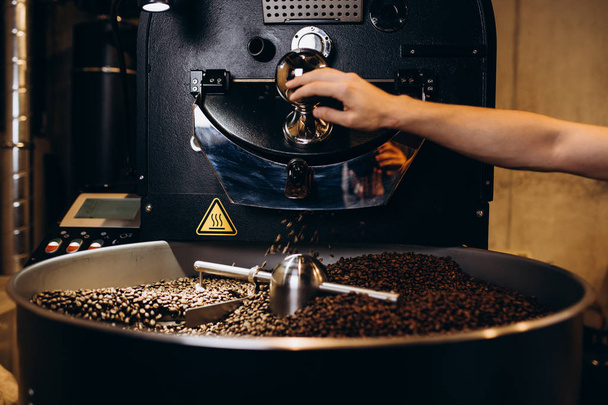 Freshly roasted coffee beans pouring from a large coffee roaster into the cooling cylinder. - Fotografie, Obrázek