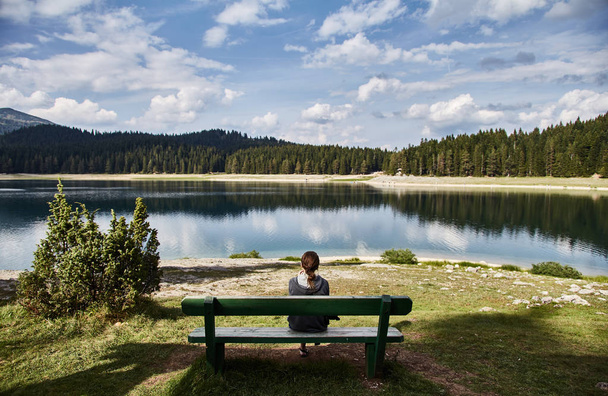 Молода дівчина сидить на лавці. Чорне озеро. Національний парк Дурмітор. Чорногорія.  - Фото, зображення