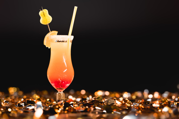 sweet cocktail with straw on golden confetti on black with copy space - Photo, image