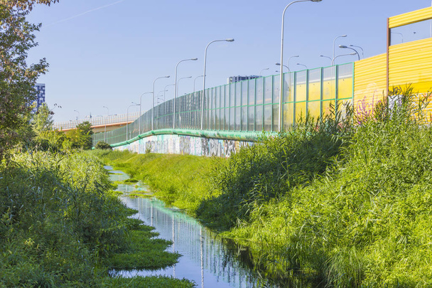 Sound-absorbing screens along the highway and the creek.Metal frames filled with glass and yellow sound-absorbing panels.Modern technology in  Poland. - Photo, Image