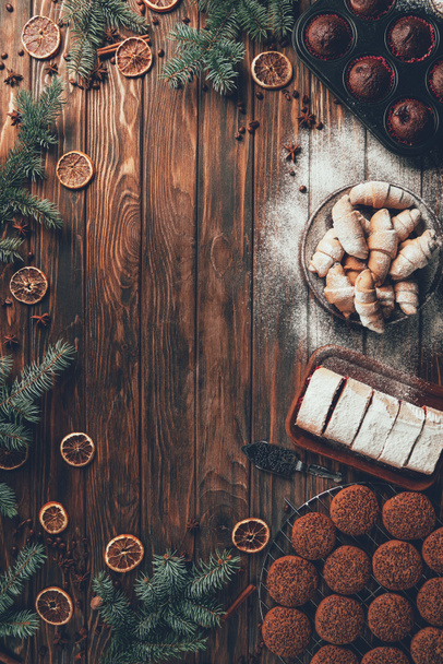 top view of tasty baked cookies, biscuit and muffins on wooden table, christmas concept - Foto, afbeelding