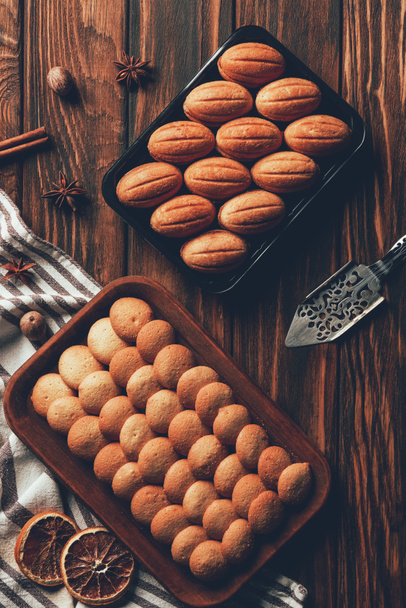 bovenaanzicht van lekkere zelfgemaakte gebakken cookies op laden op houten tafel in de bakkerij - Foto, afbeelding