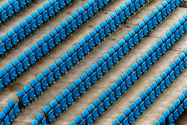 Sillas de plástico viejas en blanco en el estadio. Número de asientos vacíos en un pequeño estadio viejo. Asientos de plástico gastados rasguñados para ventiladores
 - Foto, Imagen