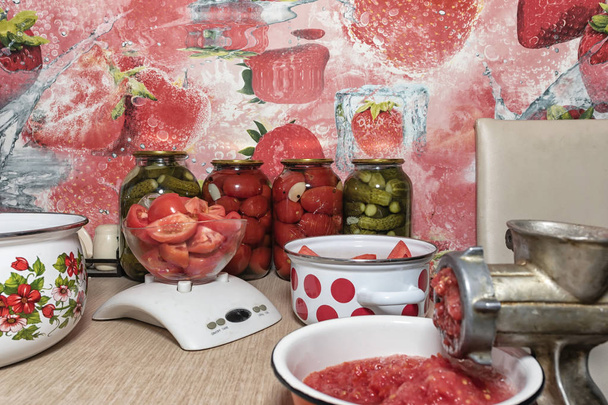 Torça tomates em purê de tomate com um velho moedor de mão. Preparação de produtos hortícolas em conserva em casa
 - Foto, Imagem