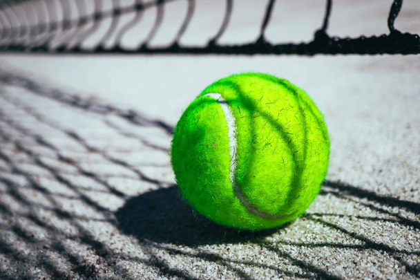 One green tennis ball on court, sport competition concept. Tennis net shadow on the ball. Macro view. - Foto, immagini