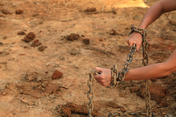 manos humanas en viejas cadenas oxidadas contra la playa de arena
 - Foto, imagen