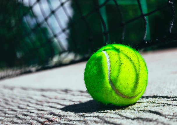 One green tennis ball on court, sport competition concept. Tennis net shadow on the ball. Macro view. - Φωτογραφία, εικόνα