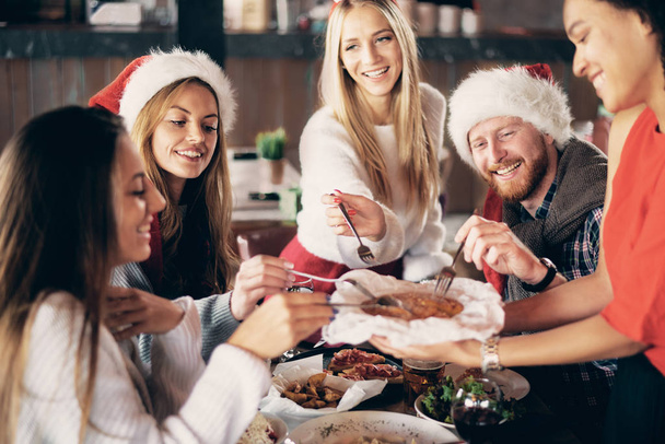 Amigos cenando en casa en Nochebuena. concepto de vacaciones de invierno
. - Foto, Imagen