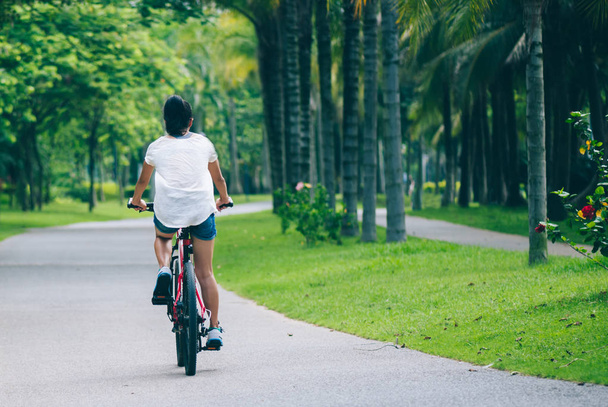 Woman riding mountain bike in tropical park - Foto, Bild