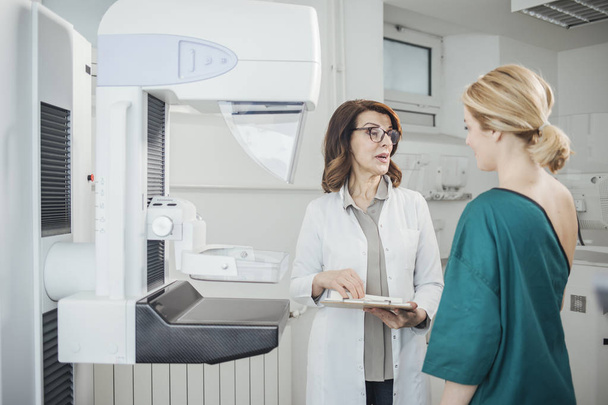 Woman oncologist talking with her patient on mammography examination. - Photo, Image