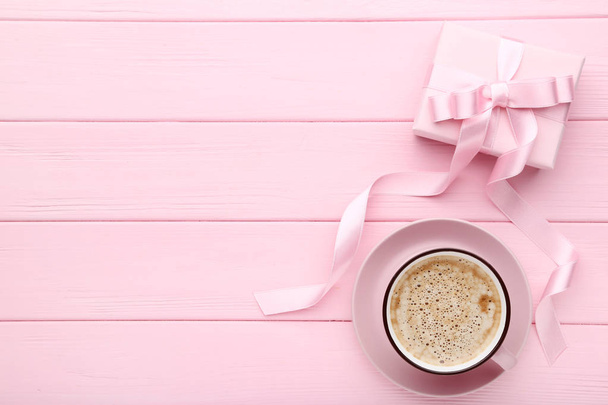 Gift box with cup of coffee on pink wooden background - Foto, Bild