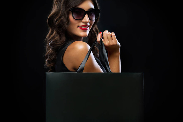 Black friday sale concept. Shopping woman holding grey bag isolated on dark background in holiday - Valokuva, kuva