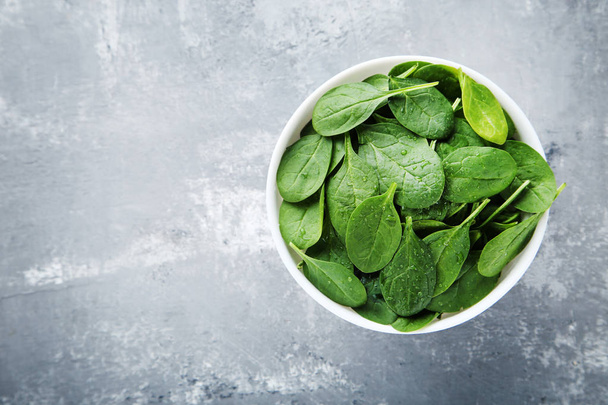 Spinach leaves in bowl on grey shabby background - Foto, Imagen