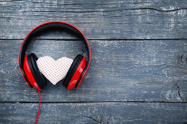Red headphones with fabric heart on wooden background - Foto, Imagem