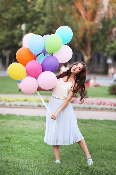 Krásná mladá dívka drží barevné balónky v parku - Fotografie, Obrázek