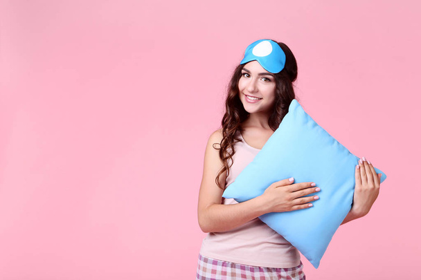 Beautiful girl with sleeping mask and pillow on pink background - Foto, Bild