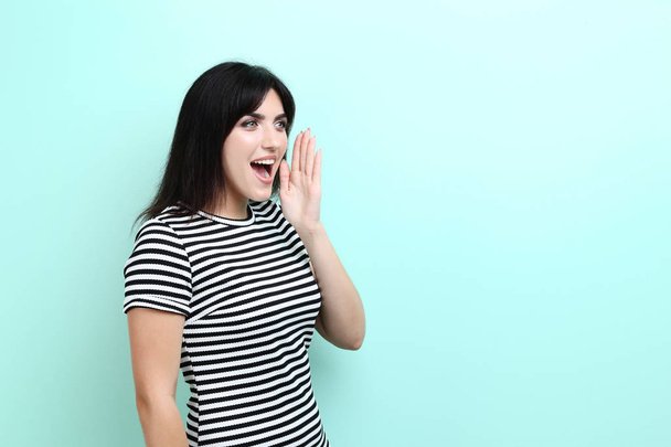 Young woman screaming on mint background - Foto, imagen