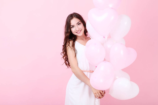 Young girl holding heart balloons on pink background - Foto, Imagem