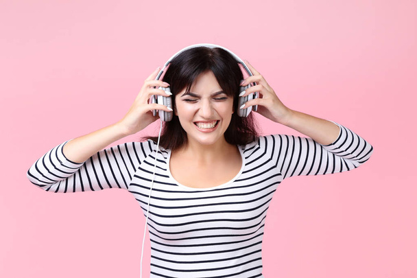 Young woman with headphones on pink background - Foto, imagen