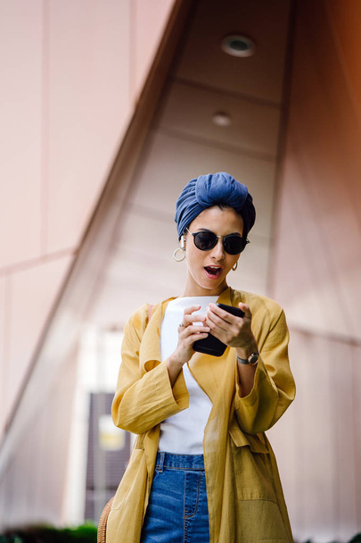 Young and attractive Malay Muslim woman holding smartphone in hands during the day - Foto, immagini