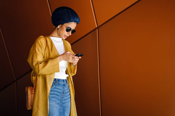 Young and attractive Malay Muslim woman holding smartphone in hands  - Foto, Imagen