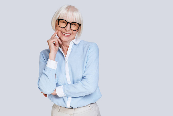 senior adult stylish woman with short grey hair posing at grey background in studio  - Foto, afbeelding