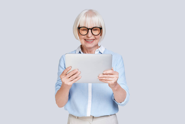 senior caucasian woman in blue shirt holding digital tablet  - Фото, изображение