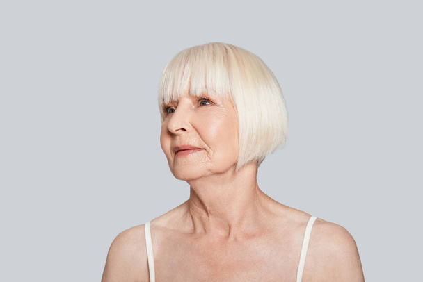 senior woman looking away and posing at grey background and looking away - Photo, image