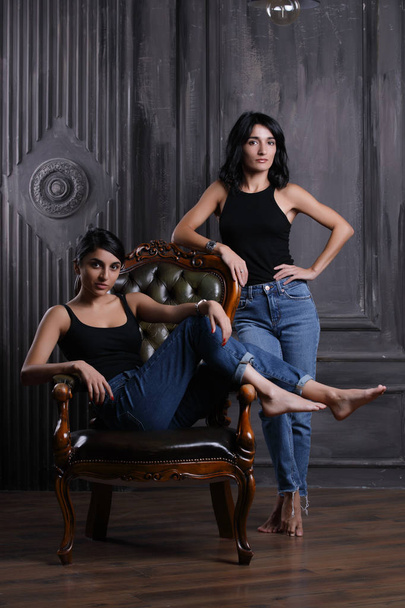 Studio portrait of two sisters on chair - Foto, afbeelding