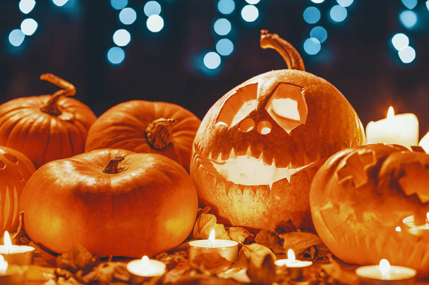 Halloween lantern, orange pumpkins, candles and autumnal leaves on a bokeh background - Фото, изображение