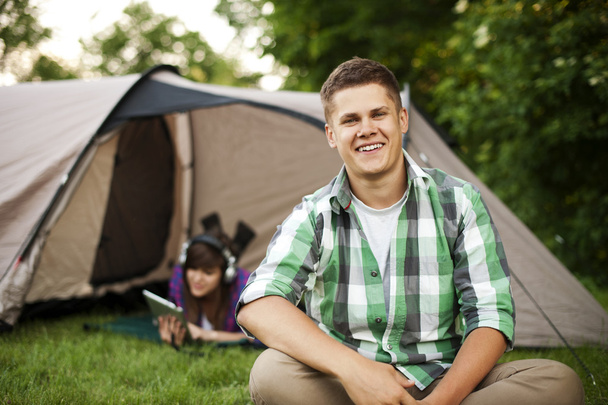 Jovem sentado na frente da tenda
 - Foto, Imagem