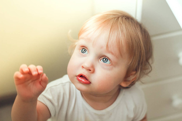 Retrato de cerca de un hermoso niño con ojos azules y cabello rubio en los rayos de luz
. - Foto, Imagen