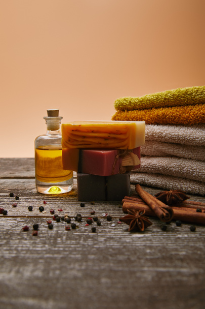 close-up shot of soap pieces with stacked towels, spices and massage oil on rustic wooden tabletop - Photo, Image