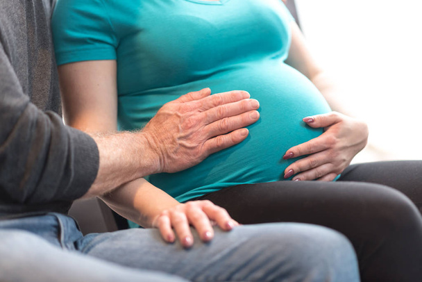 Пара держащихся за руки на беременном животе
 - Фото, изображение