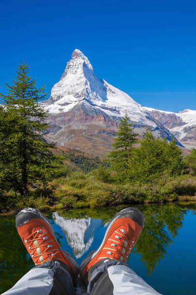 Matterhorn peak with hiking boots in Swiss Alps. - Photo, Image