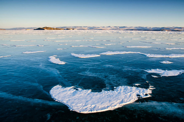 Vista di bei disegni su ghiaccio da incrinature e bolle di gas profondo su superficie di lago di Baikal in inverno con montagna, Russia
 - Foto, immagini