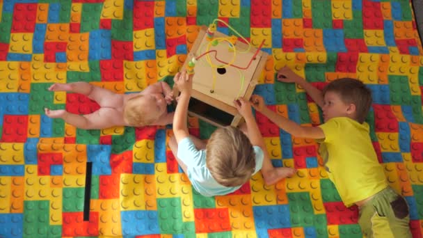 Tres niños jugando con juguetes. Fondo brillante alfombra de colores. Vida pre-enfriamiento. Diferentes niños mayores. Brain juegos de desarrollo
. - Imágenes, Vídeo