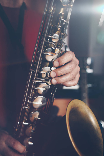 Close up shot of musician playing saxophone. Low light and selective focus. - Фото, изображение