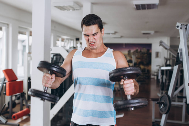 Young attractive adult man exercising at fitness gym. Sport training indoors. - Fotoğraf, Görsel
