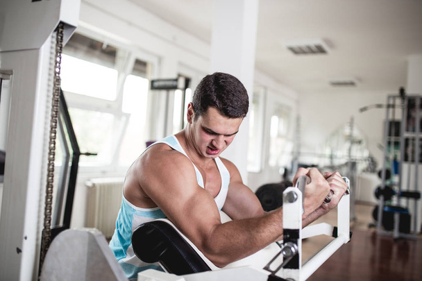 Young attractive adult man exercising at fitness gym. Sport training indoors. - Foto, immagini