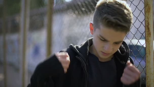 Boy leaning on fence, wearing hoodie, orphan in boarding school, confinement - 映像、動画