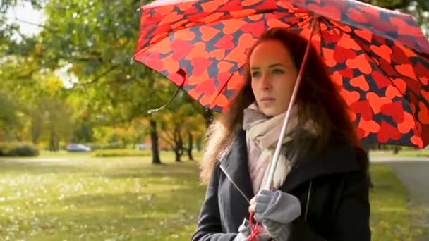 Hermosa dama con gran paraguas rojo caminando en el parque en otoño dorado
 - Metraje, vídeo