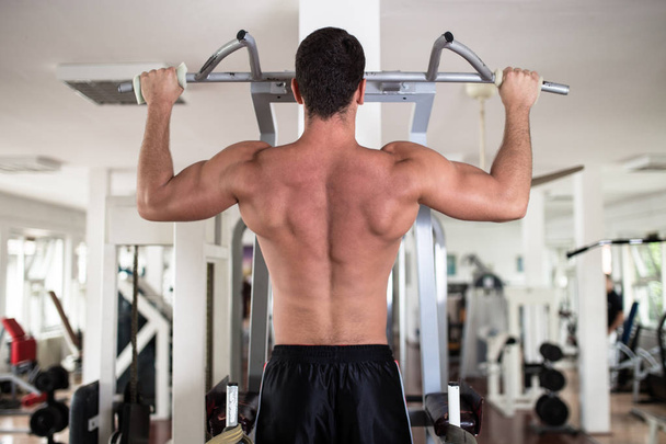 Young attractive adult man exercising at fitness gym. Sport training indoors. - Foto, Imagem