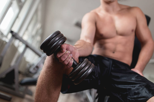Young attractive adult man exercising and doing weight lifting at fitness gym. Sport training indoors. - Foto, afbeelding