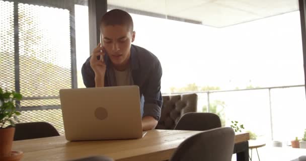Man talking on mobile phone while using laptop at home 4k - Video, Çekim