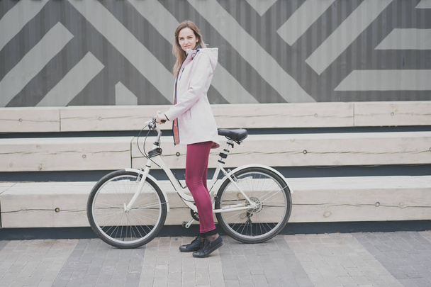 Lifestyle sport concepte. Sexy young woman with vintage bike in city parking. Nature color toning for design - Фото, зображення