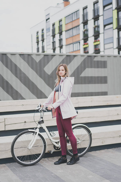Lifestyle sport concepte. Sexy young woman with vintage bike in city parking. Nature color toning for design - Фото, зображення