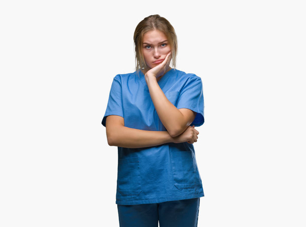 Jeune infirmière caucasienne portant l'uniforme de chirurgien sur fond isolé pensant fatigué et ennuyé avec des problèmes de dépression avec les bras croisés
. - Photo, image
